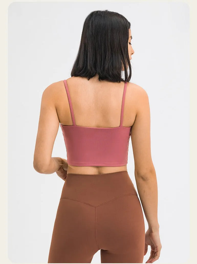 Frau in rosa Sport-BH und brauner Leggings von hinten. Fitnessmode, bequeme Sportbekleidung, trendige Activewear für Damen.