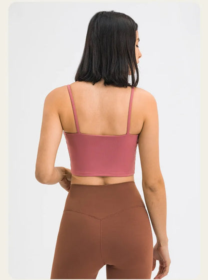 Frau in rosa Sport-BH und brauner Leggings von hinten. Fitnessmode, bequeme Sportbekleidung, trendige Activewear für Damen.