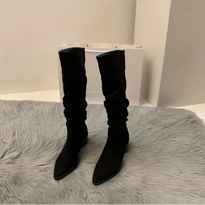 Schwarze Stiefel mit spitzem Absatz auf grauem Fellteppich, modisch und elegant, ideal für Herbst- und Winteroutfits. Damenmode, Schuhe.