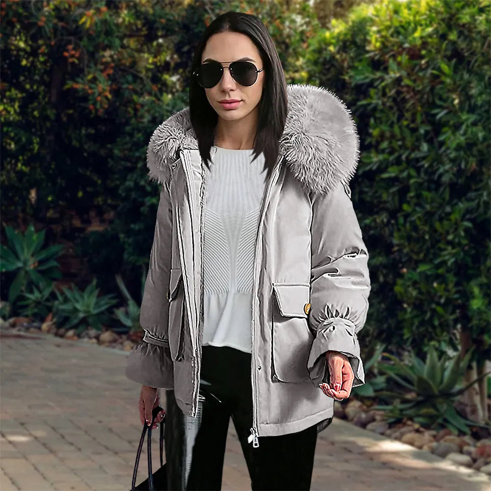 Frau in grauer Winterjacke mit Fellkapuze, Sonnenbrille und schwarzer Hose. Modetrend, Wintermode, stilvolle Damenbekleidung, Outdoor.