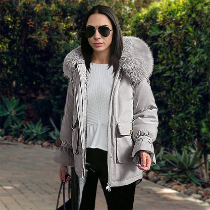 Frau in grauer Winterjacke mit Fellkapuze, Sonnenbrille und schwarzer Hose. Modetrend, Wintermode, stilvolle Damenbekleidung, Outdoor.