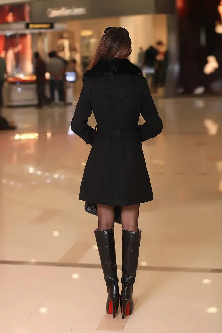 Eleganter schwarzer Wintermantel für Damen, kombiniert mit kniehohen Stiefeln. Perfekt für stilvolle Wintermode und trendige Outfits.