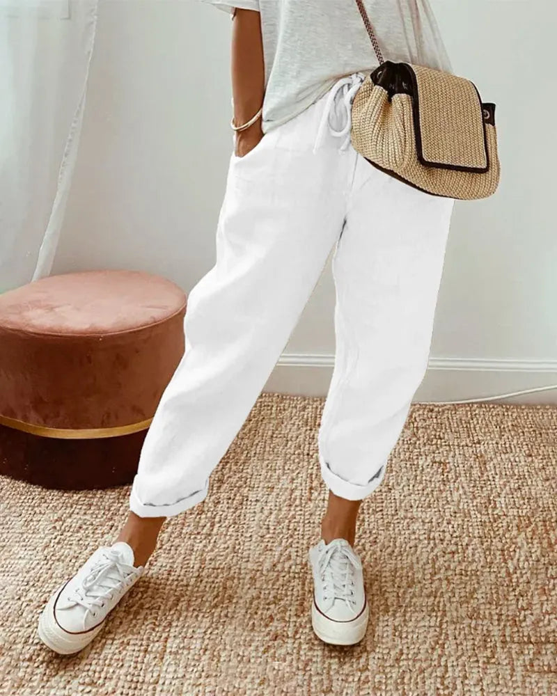 Damenmode: Weiße Leinenhose, lässig und bequem, kombiniert mit Sneakers und Strohtasche. Perfekt für Sommer-Outfits und Freizeit-Looks.