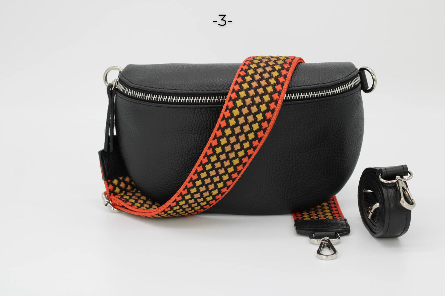 Schwarze Lederhandtasche mit auffälligem, gemustertem Schultergurt. Modisches Accessoire, ideal für Damen. Hochwertige Verarbeitung.