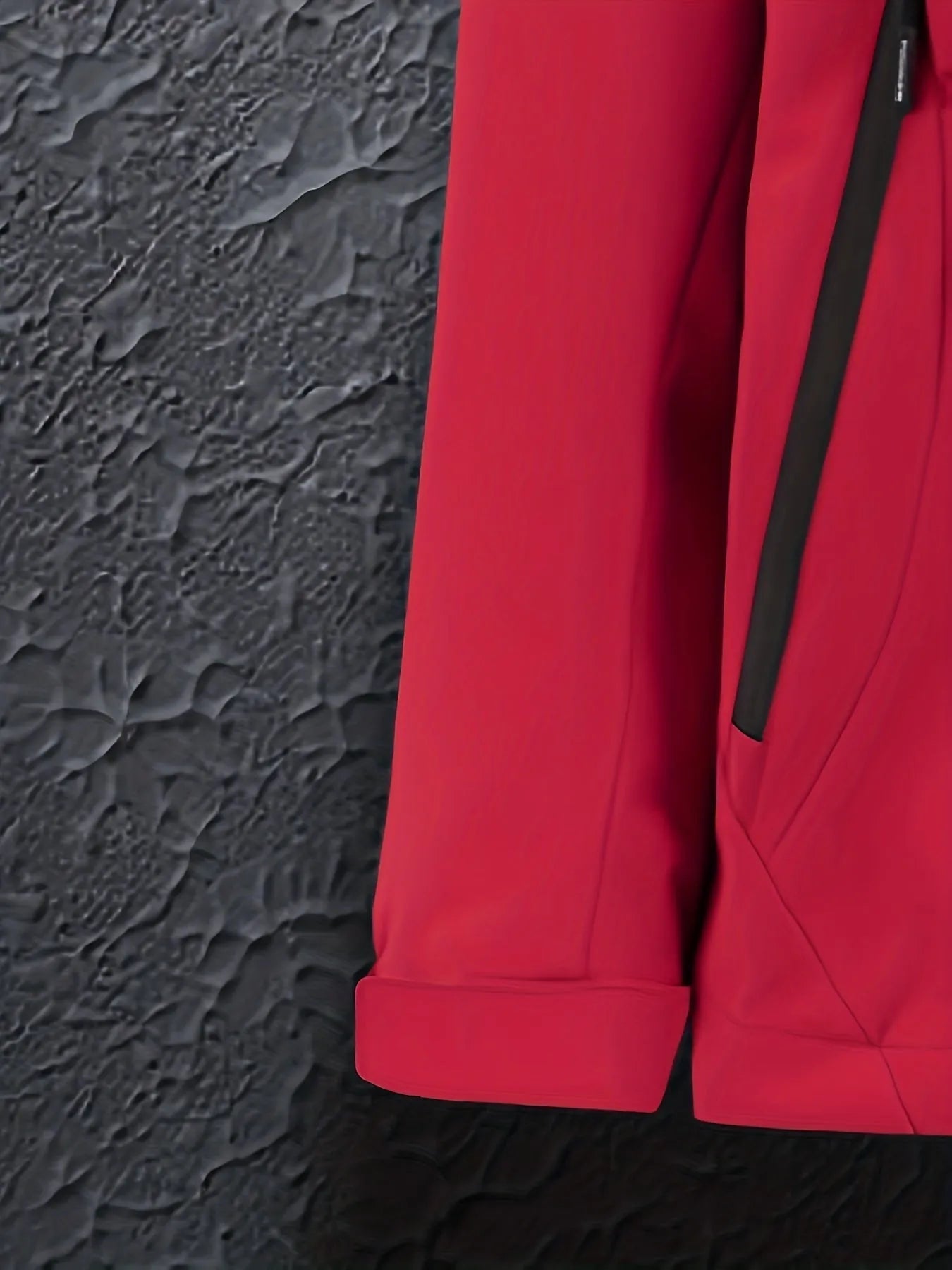 Rote Jacke mit schwarzem Reißverschluss vor strukturiertem Hintergrund. Modische Outdoor-Bekleidung, ideal für Herbst und Winter.