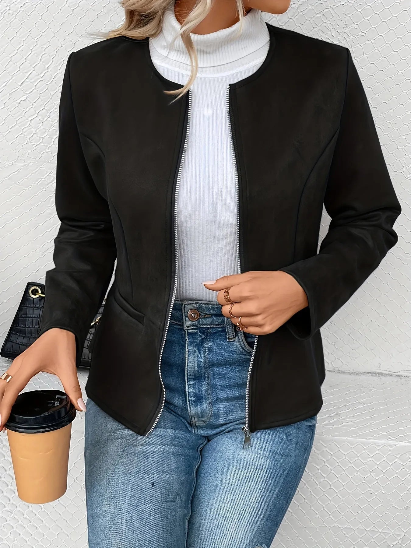 Damenjacke in Schwarz, elegant und modern, kombiniert mit weißem Rollkragenpullover und blauer Jeans. Perfekt für stilvolle Herbstmode.