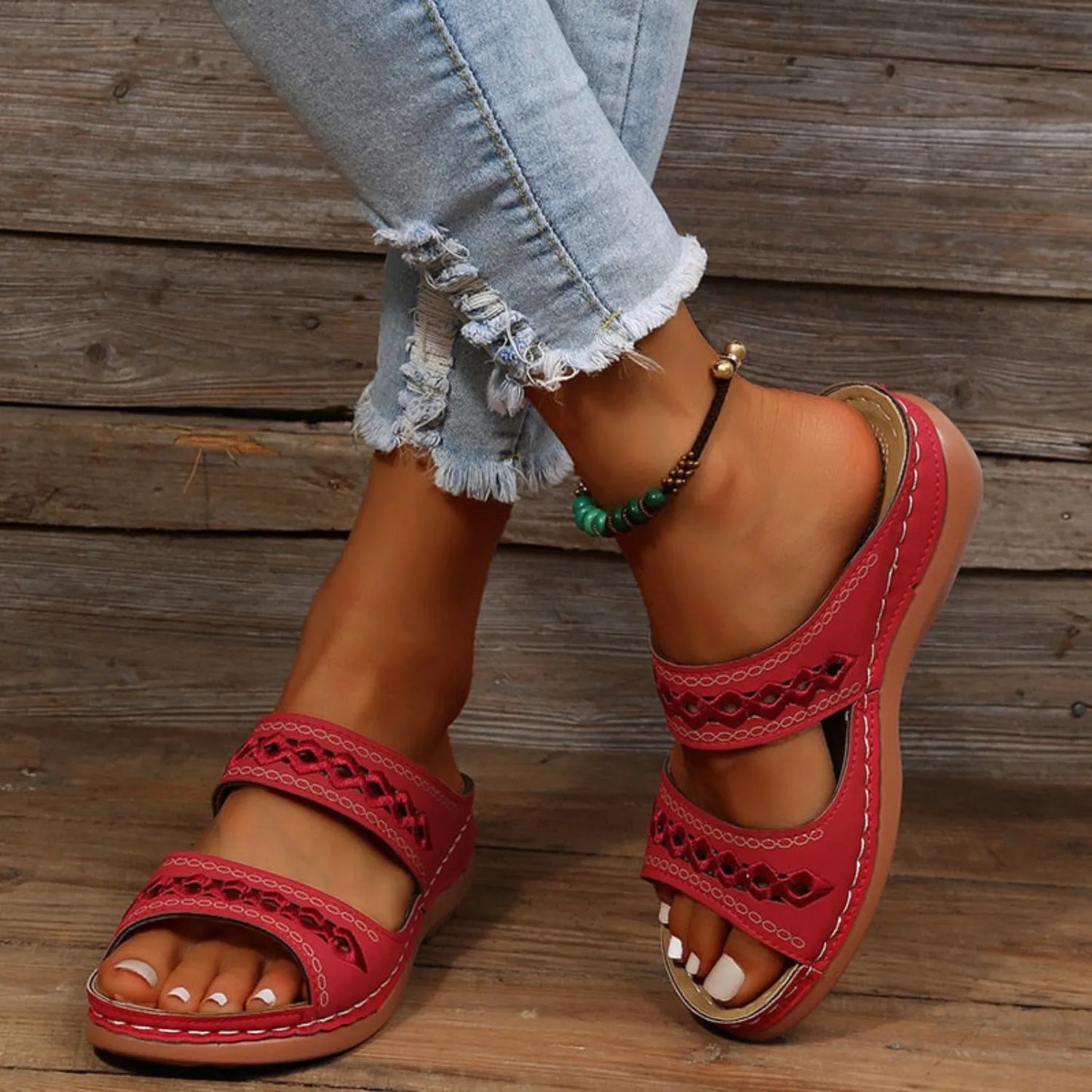Rote Sandalen mit Cut-Out-Design, bequemem Fußbett und verstellbaren Riemen, kombiniert mit modischen, zerrissenen Jeans. Perfekt für den Sommer.
