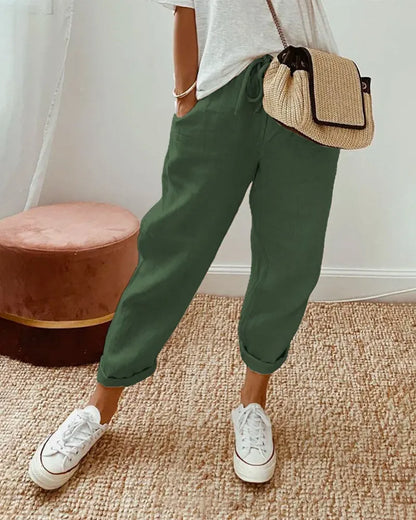 Damenhose in Grün, lässig und bequem, kombiniert mit weißen Sneakers und einer Strohtasche. Perfekt für Freizeitmode und Sommeroutfits.