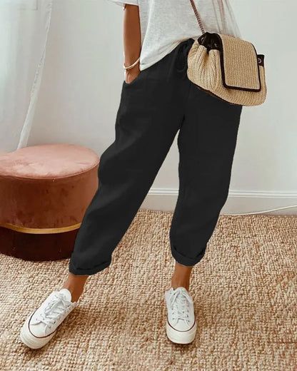 Damenmode: Lässige schwarze Jogginghose, kombiniert mit weißen Sneakers und beiger Umhängetasche. Perfekt für Freizeit und Streetstyle.