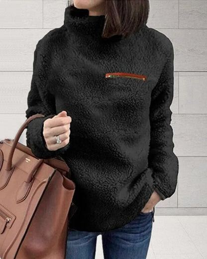 Damen-Fleecejacke in Schwarz mit hohem Kragen und Reißverschlusstasche, kombiniert mit brauner Ledertasche. Perfekt für Herbstmode.