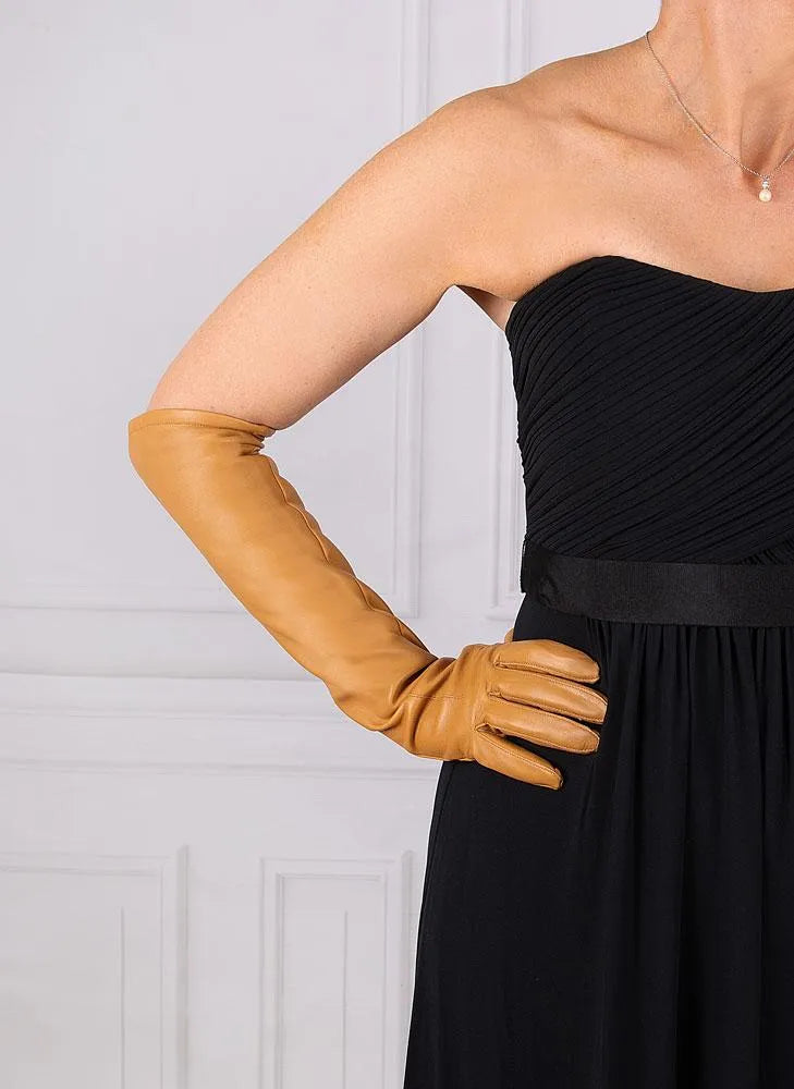 Damenlederhandschuh in Camel, elegant und lang, kombiniert mit schwarzem Abendkleid. Perfekt für stilvolle Anlässe und modische Akzente.