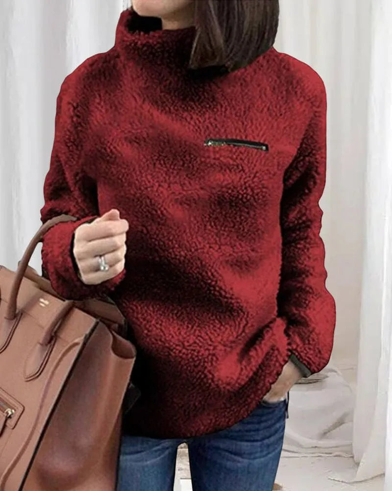 Damenmode: Roter Teddy-Fleece-Pullover mit hohem Kragen und Reißverschlussdetail, kombiniert mit brauner Handtasche. Perfekt für Herbst/Winter.