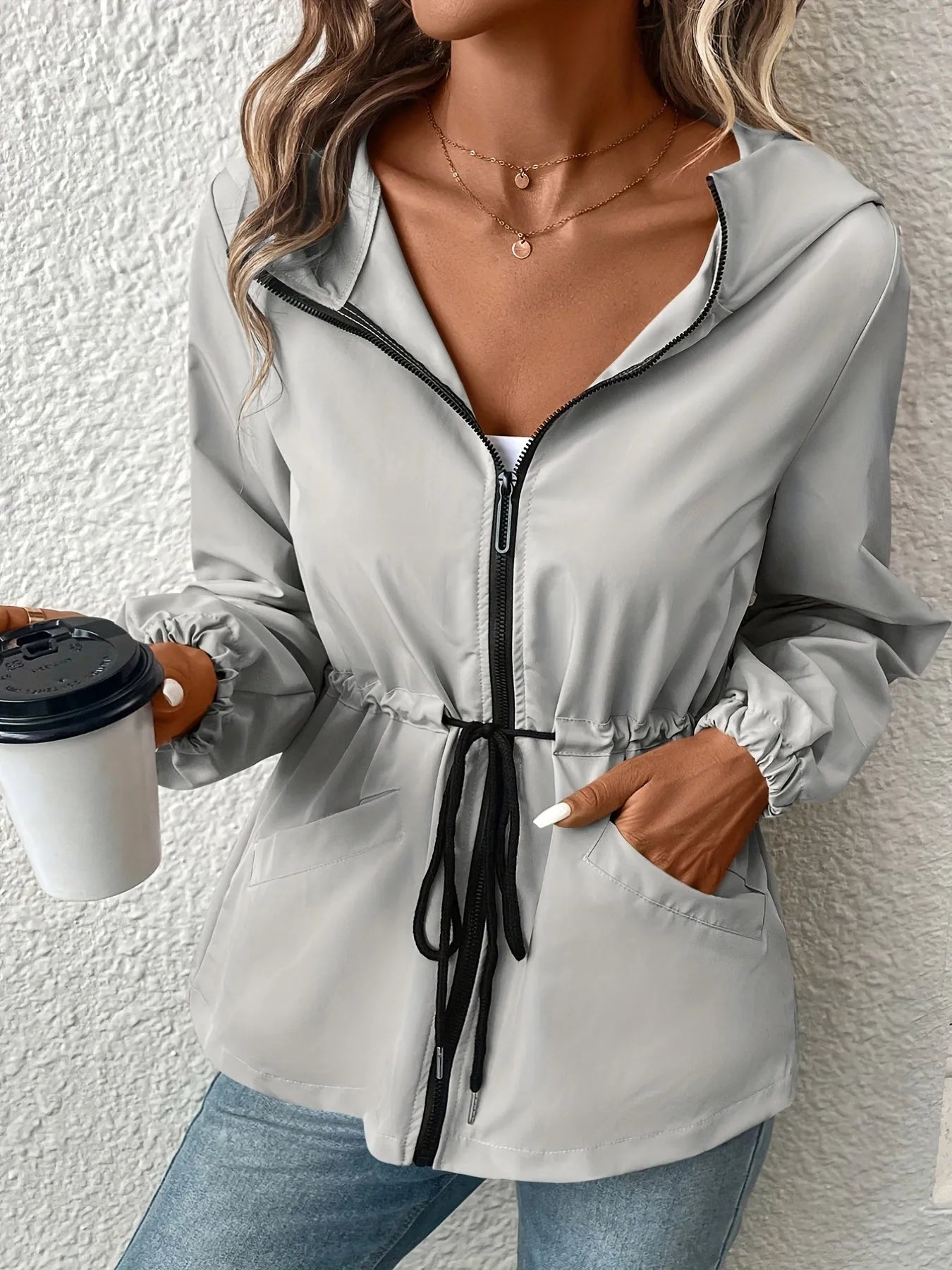Damenjacke mit Kapuze, Reißverschluss und Kordelzug in Grau. Perfekt für den Herbst. Modische Freizeitkleidung, ideal für kühle Tage.