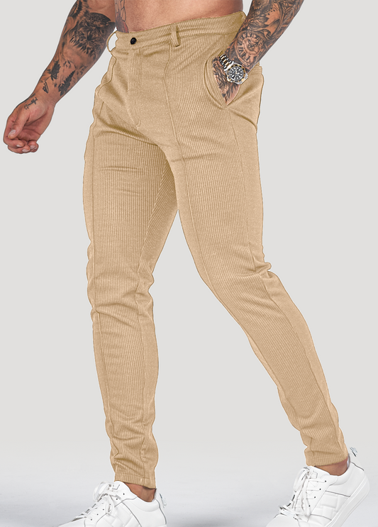 Beige Herren-Chinohose, schmal geschnitten, aus Baumwolle, kombiniert mit weißen Sneakers.