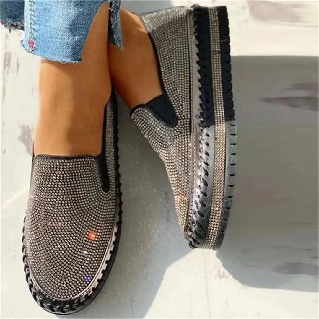 Elegante schwarze Slip-On-Schuhe mit funkelnden Strasssteinen, ideal für Damenmode. Perfekt für stilvolle Anlässe und trendige Outfits.