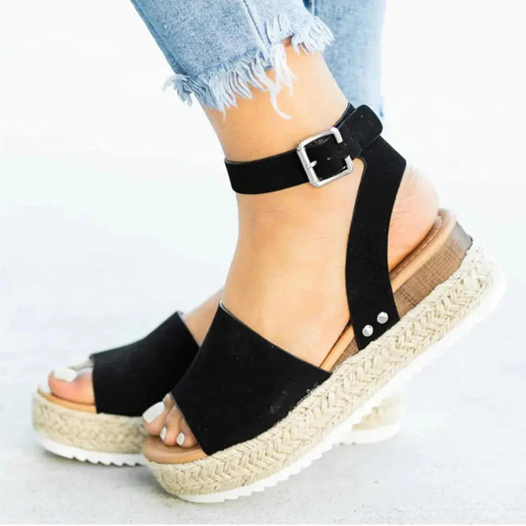 Schwarze Sandalen mit Keilabsatz und Schnalle, kombiniert mit hellblauen Jeans. Perfekt für Sommermode und lässige Outfits.
