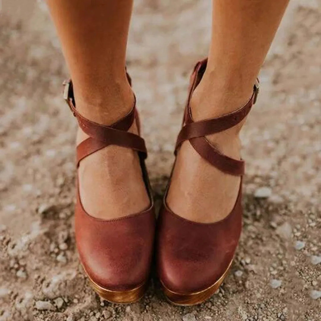 Braune Damen-Sandalen mit Kreuzriemen, aus Leder, auf sandigem Untergrund. Perfekt für Sommermode, bequem und stilvoll. Ideal für Freizeitkleidung.
