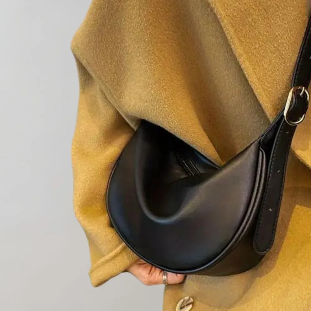 Schwarze Lederhandtasche in Halbmondform, elegant und modern, ideal für Damenmode. Perfekt für stilvolle Outfits und trendige Accessoires.