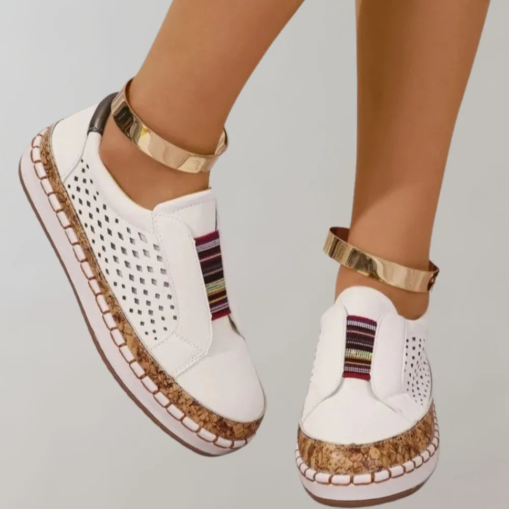 Weiße Damen-Sneaker mit perforiertem Design, bunten Streifen und goldenen Knöchelriemen. Modische, bequeme Schuhe für den Sommer.