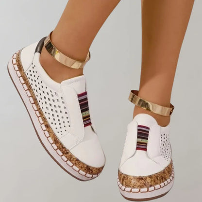 Weiße Damen-Sneaker mit perforiertem Design, bunten Streifen und goldenen Knöchelriemen. Modische, bequeme Schuhe für den Sommer.