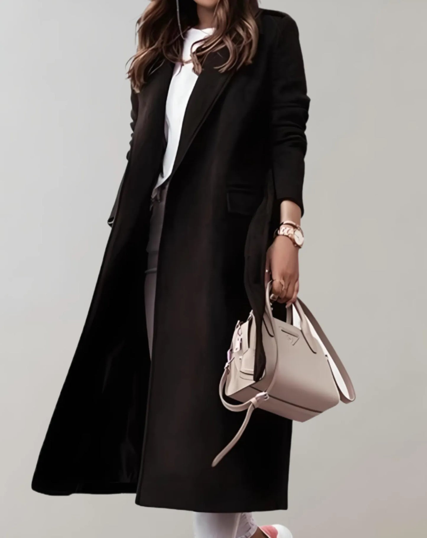 Eleganter schwarzer Damenmantel, kombiniert mit weißem Oberteil und beiger Handtasche. Perfekt für stilvolle Herbst- und Wintermode.