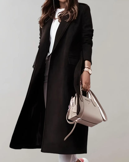 Eleganter schwarzer Damenmantel, kombiniert mit weißem Oberteil und beiger Handtasche. Perfekt für stilvolle Herbst- und Wintermode.