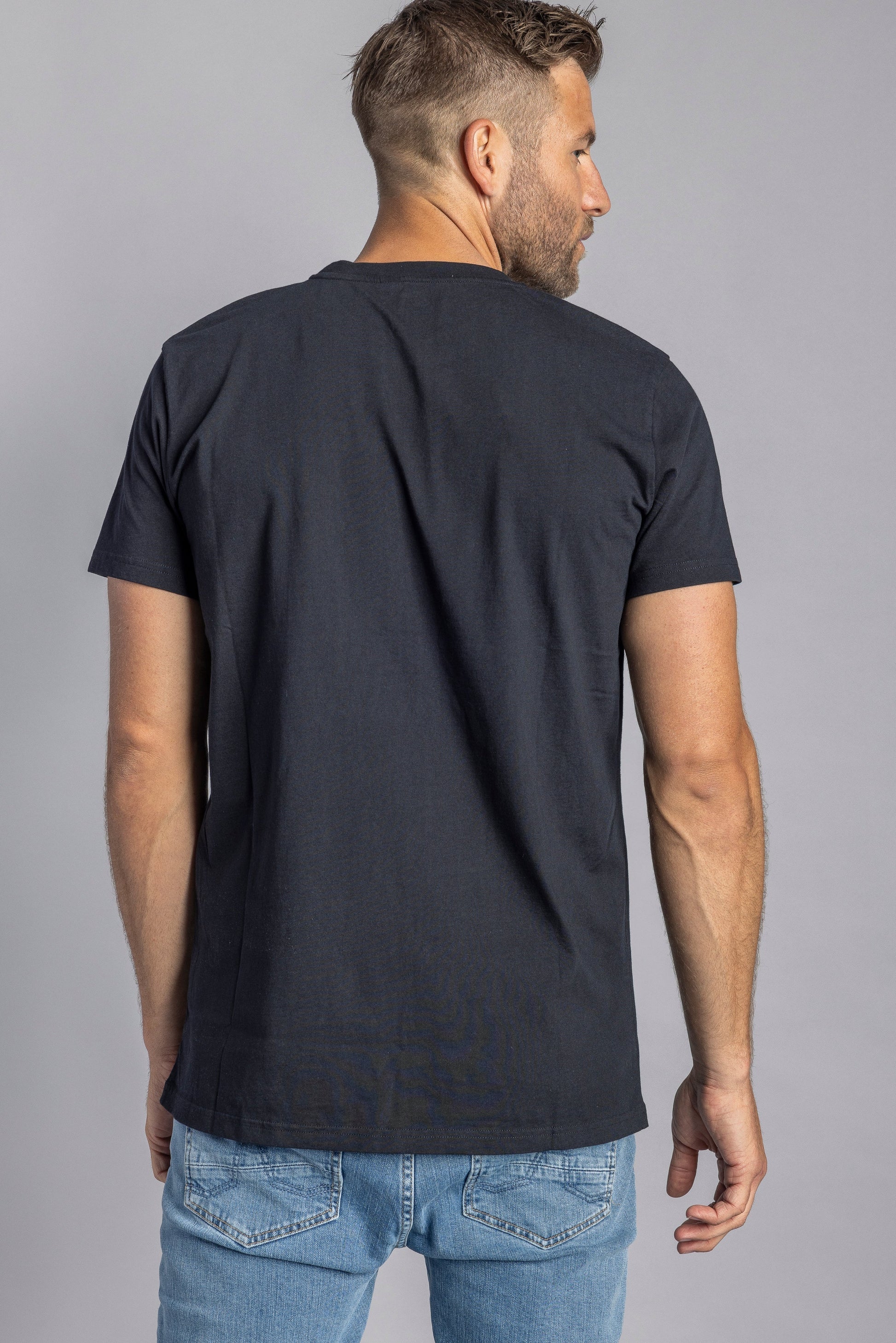 Mann in schwarzem T-Shirt und blauer Jeans von hinten, lässige Herrenmode, Freizeitkleidung.