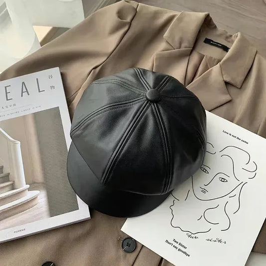 Schwarze Leder-Newsboy-Mütze auf braunem Mantel, stilvoll und modern. Perfekt für Herbst und Winter. Trendige Damenmode, koreanischer Stil.