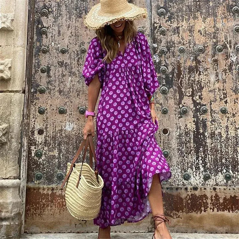 Boho Maxi Kleid mit V-Ausschnitt und Laternenärmeln, lila Druck, ideal für Sommerurlaub. Perfekt kombiniert mit Strohhut und Korbtasche.