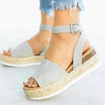 Graue Sandalen mit Plateau, Knöchelriemen und Schnalle, ideal für Sommermode. Bequeme Damen-Schuhe mit Bastsohle und modernem Design.