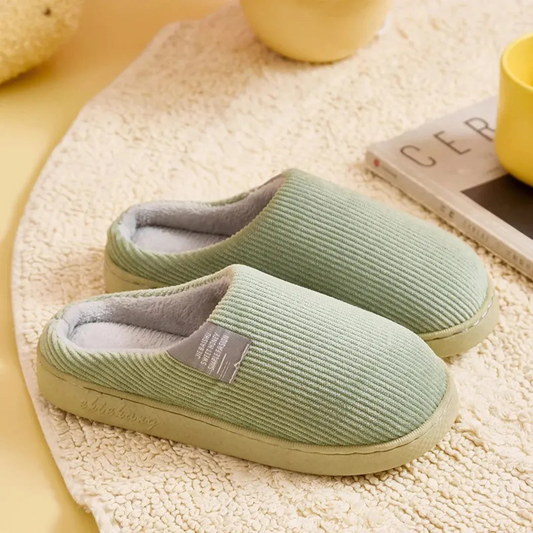 Grüne Hausschuhe aus weichem Stoff auf Teppich, ideal für gemütliche Winterabende. Bequeme Pantoffeln, perfekt für Zuhause und Entspannung.