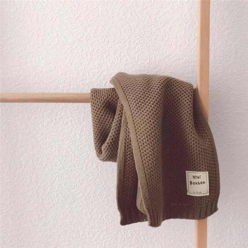 Braune Strickdecke auf Holzleiter, weiches Material, ideal für gemütliche Wohnräume. Perfekt als stilvolles Wohnaccessoire oder Geschenk.