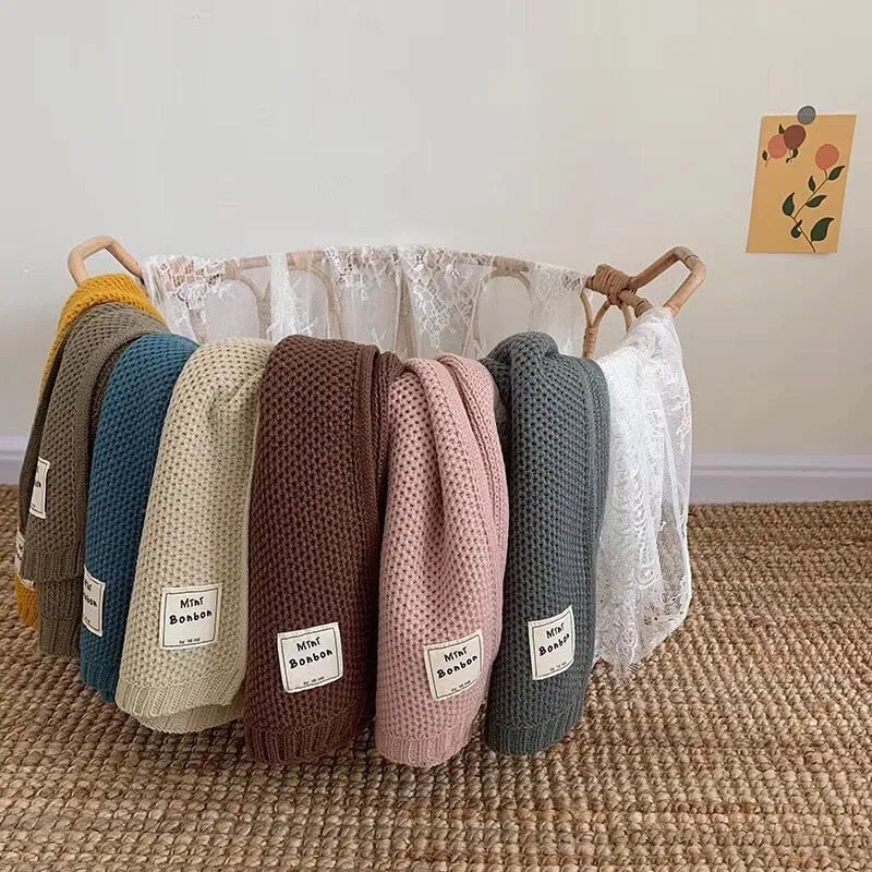 Bunte Babydecken in einem Korb, gestrickt aus weicher Baumwolle. Perfekt für Neugeborene, ideal als Geschenk. Hochwertige Babytextilien online kaufen.