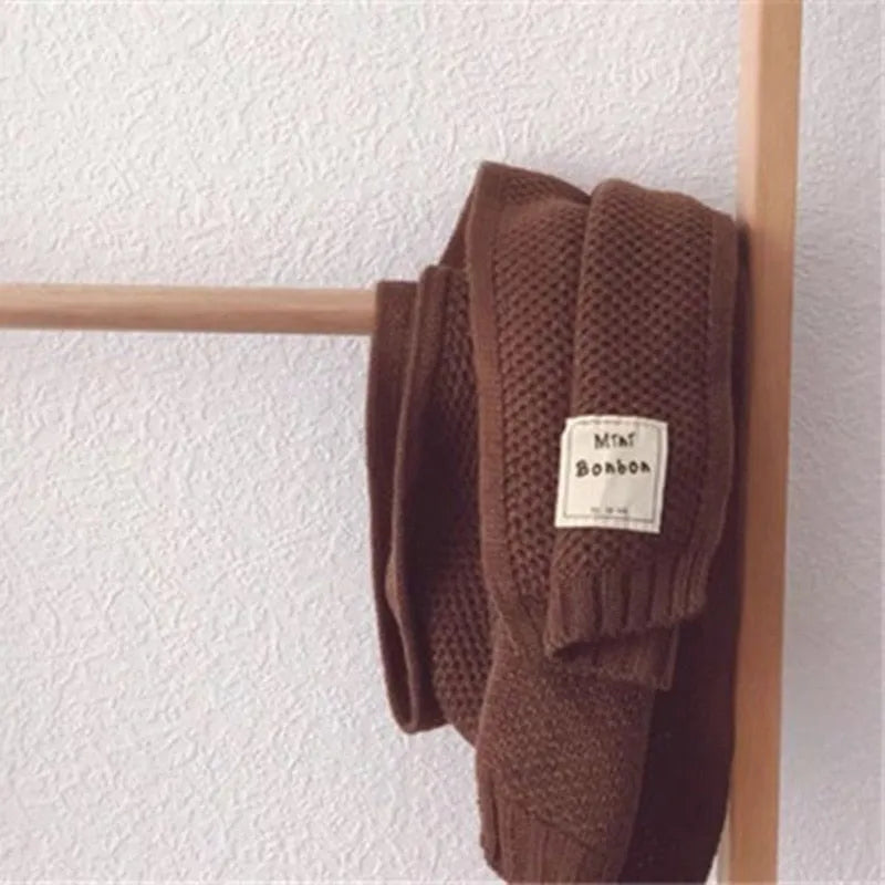 Brauner Strickpullover mit Etikett "MIA Bonbon" auf Holzkleiderbügel, minimalistisch, gemütlich, Herbstmode, hochwertiger Strick, stilvoll.