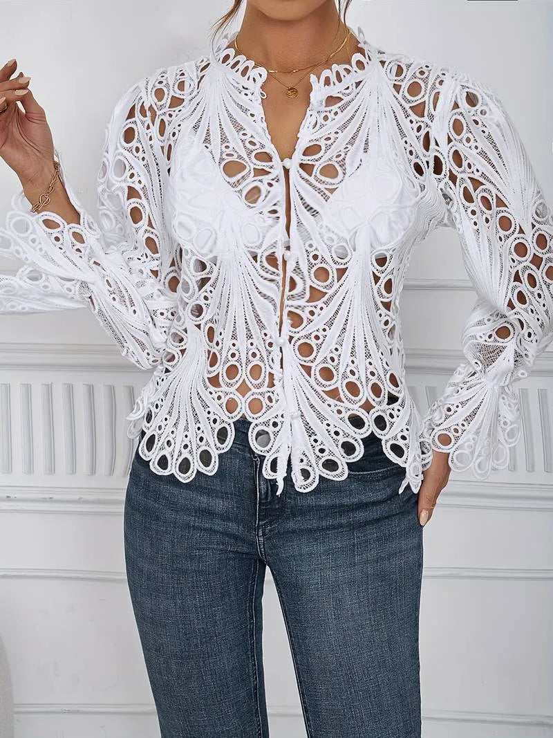 Elegante weiße Spitzenbluse mit aufwendigem Lochmuster, kombiniert mit blauen Jeans. Perfekt für stilvolle, modische Outfits und besondere Anlässe.