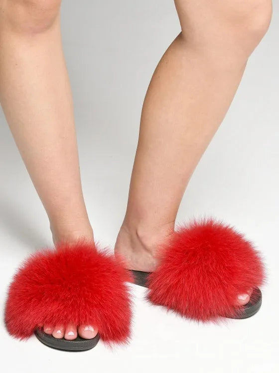 Rote flauschige Hausschuhe auf schwarzen Sohlen, getragen von einer Person. Perfekt für gemütliche Abende. Trendige Damenmode, bequeme Pantoffeln.