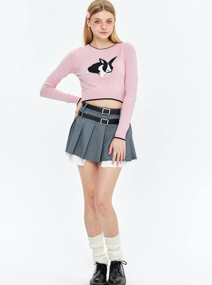Damenmode: Rosa Pullover mit Hasenmotiv, grauer Faltenrock, schwarze Stiefel. Trendige Kleidung, jugendlicher Stil, modisches Outfit.