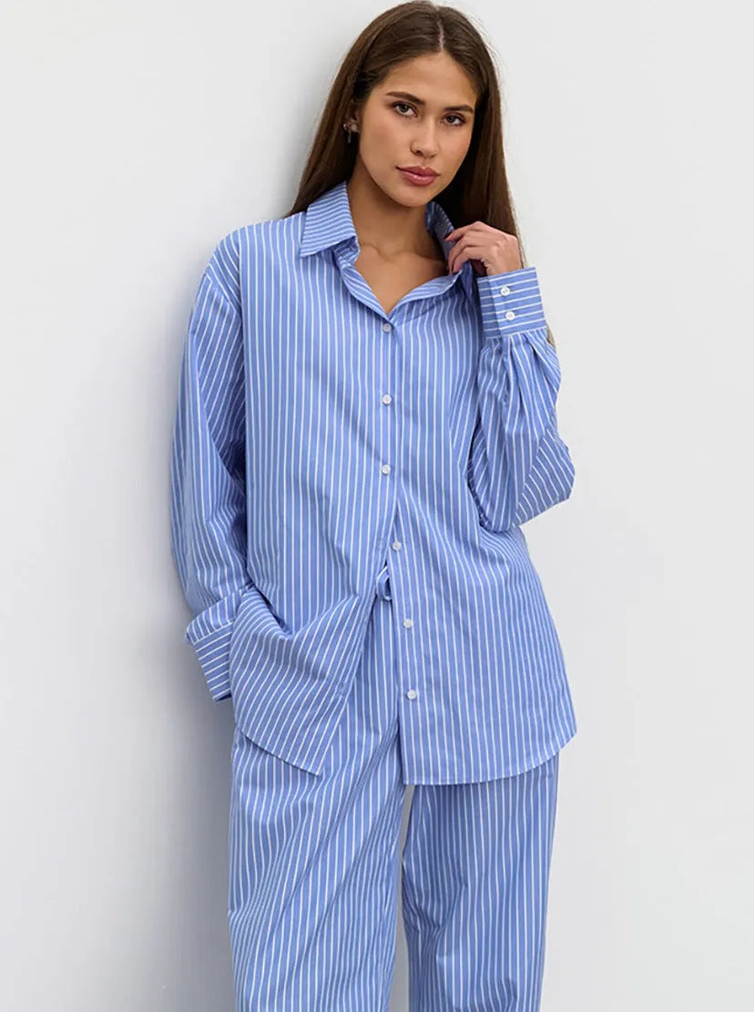 Frau in gestreiftem, blau-weißem Pyjama-Set aus Baumwolle, lässig und bequem, ideal für Nachtwäsche oder entspannte Tage zu Hause.