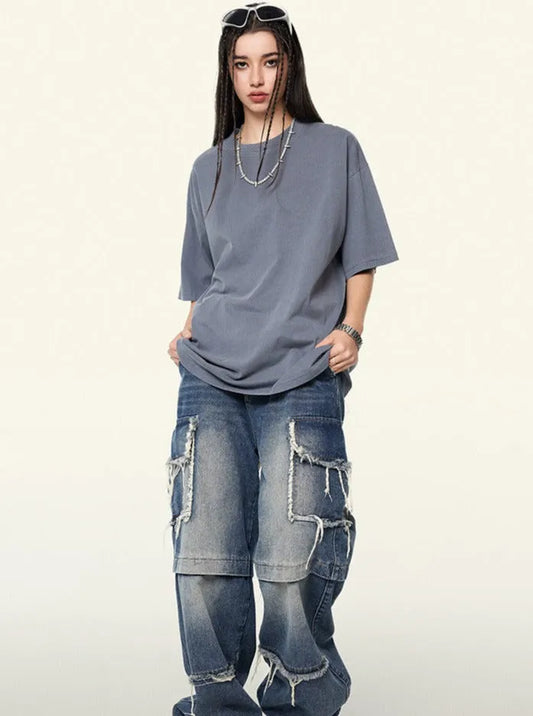 Frau in lässigem Outfit: Graues T-Shirt, weite Jeans mit Rissen, Sonnenbrille. Streetwear, urbaner Stil, modische Freizeitkleidung.