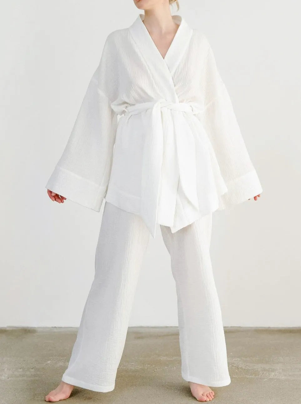 Frau in weißem Kimono-Set aus Baumwolle, ideal für entspannte Tage. Bequeme, stilvolle Loungewear für Damen. Perfekt für Zuhause oder Spa.