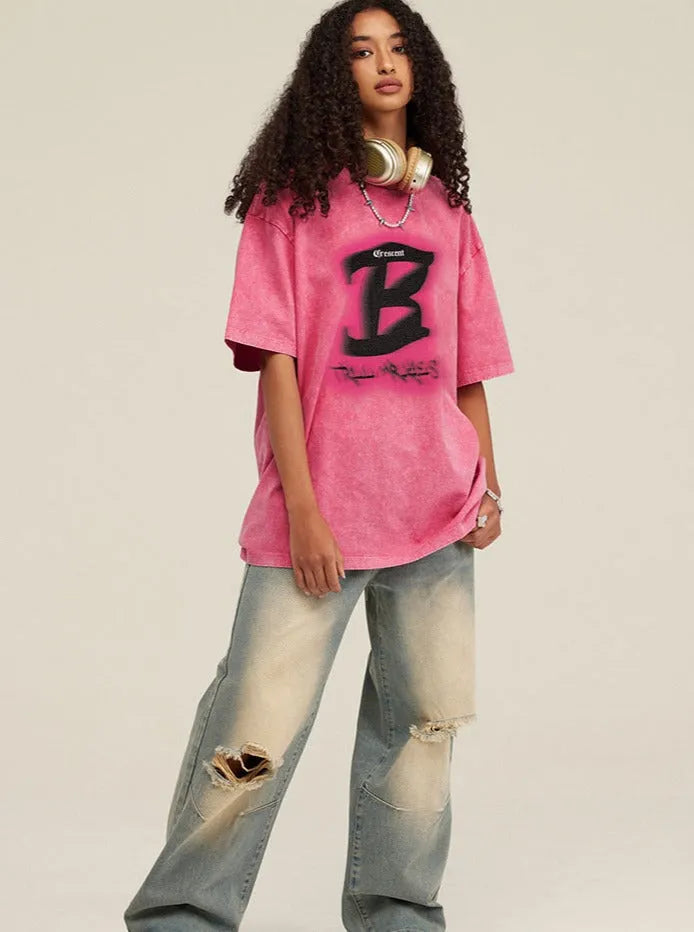 Frau in rosa Oversize-T-Shirt mit schwarzem Logo, zerrissene Jeans und Kopfhörern. Trendige Streetwear-Mode, lässiger urbaner Stil.