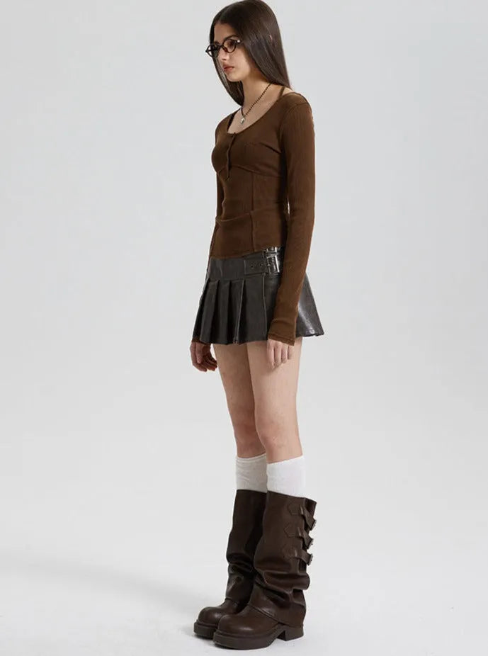 Frau in braunem Langarmshirt, schwarzem Faltenrock und hohen Stiefeln. Modetrend, Herbstmode, Damenbekleidung, stilvoll, modern.