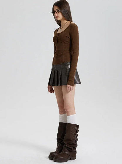 Frau in braunem Langarmshirt, schwarzem Faltenrock und hohen Stiefeln. Modetrend, Herbstmode, Damenbekleidung, stilvoll, modern.