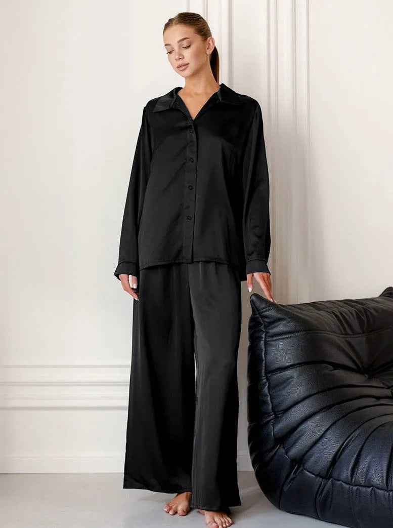 Elegantes schwarzes Pyjama-Set aus Satin für Damen, bestehend aus langärmligem Hemd und weiten Hosen. Perfekt für stilvolle Nachtmode.