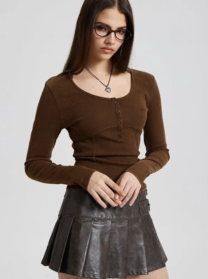 Frau in braunem Langarmshirt und schwarzem Lederrock, modisch, elegant, Brille, Herzanhänger, trendige Damenmode, stilvolles Outfit.