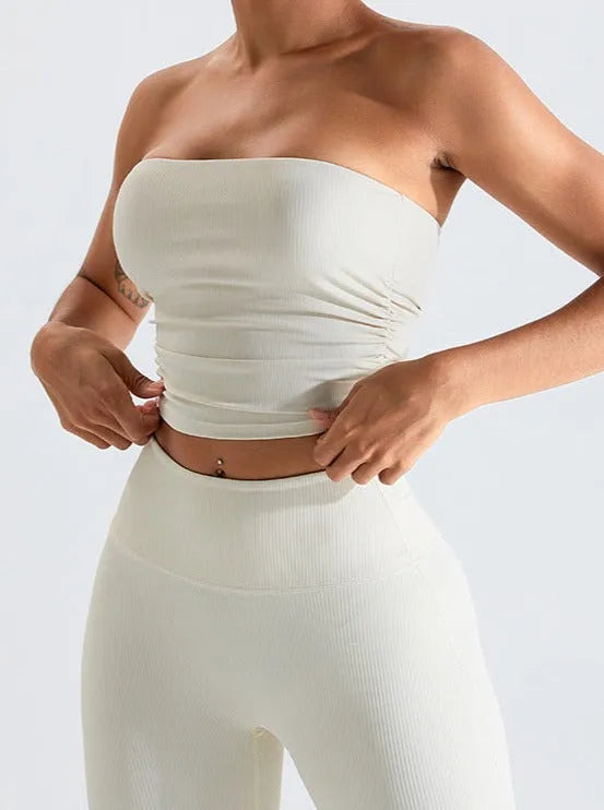 Frau in nahtlosem, cremefarbenem Tube-Top und Leggings. Sportbekleidung, Fitnessmode, bequeme Damenbekleidung, nahtloses Design.