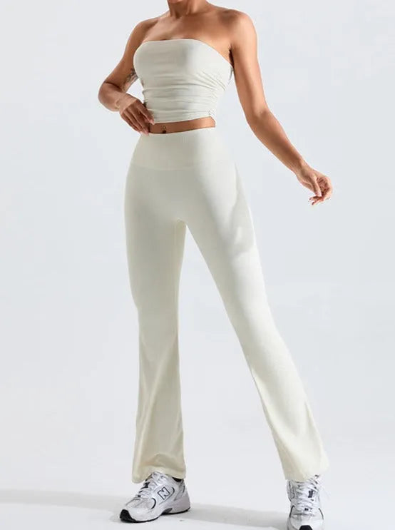Damen-Set aus cremefarbenem, schulterfreiem Top und ausgestellter Hose. Perfekt für Freizeitmode, bequem und stilvoll. Ideal für den Sommer.