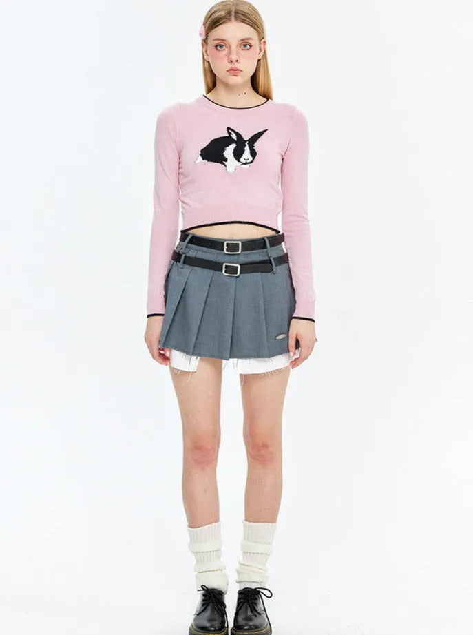 Damenmode: Rosa Crop-Top mit Hasenmotiv, grauer Faltenrock, weiße Socken, schwarze Schuhe. Trendige Kleidung, jugendlicher Stil, modisch.