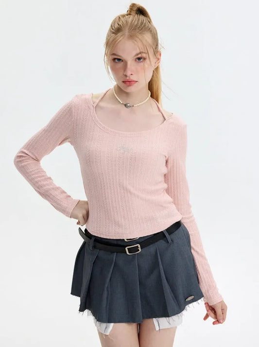 Junge Frau in rosa Pullover und grauem Faltenrock, modisch und elegant. Perfekt für trendige Damenmode, Herbstoutfits, stilvolle Kleidung.