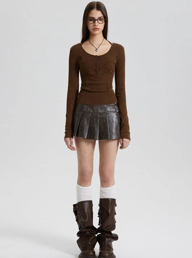 Frau in braunem Langarmshirt, schwarzem Faltenrock und hohen Stiefeln. Modetrend, Herbstmode, Damenbekleidung, stilvoll, urban.